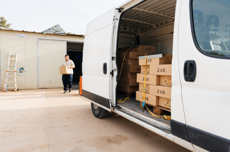 Young man exiting a warehouse with carton box in hands